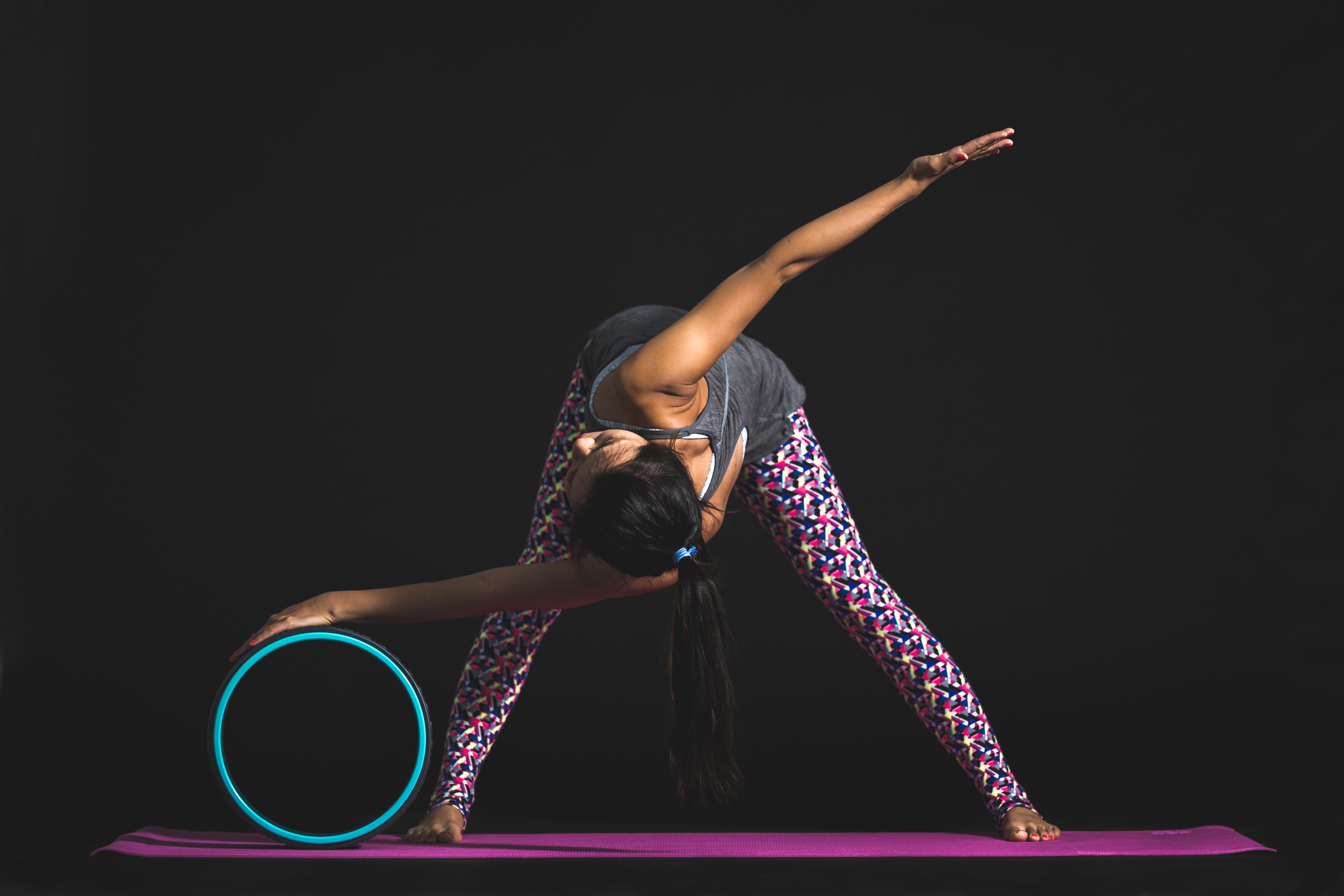 Woman doing a twist on a yoga wheel with a black background